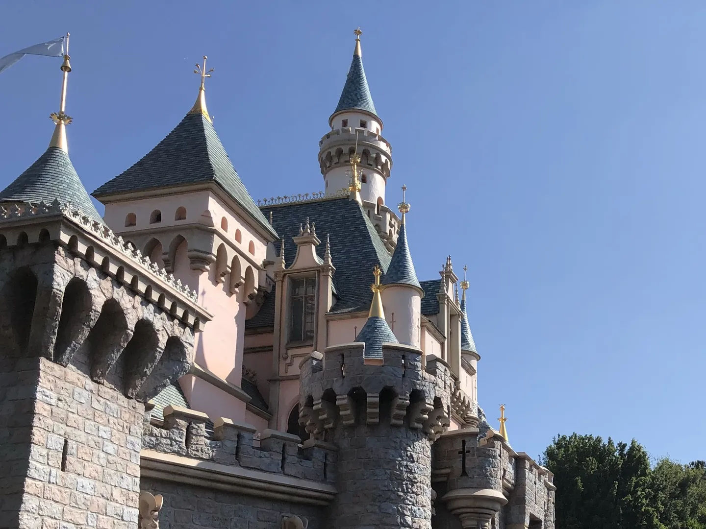 Pink and gray turrets of Sleeping Beauty Castle at Disneyland against a blue sky