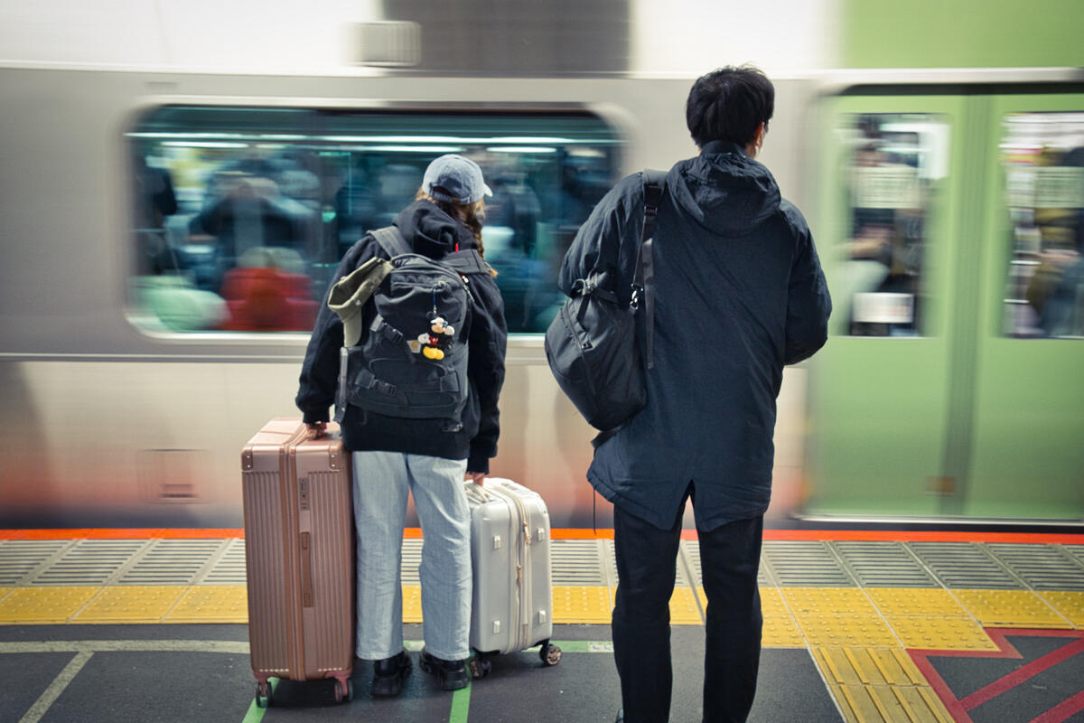 Travelers with suitcases at a Japanese train station